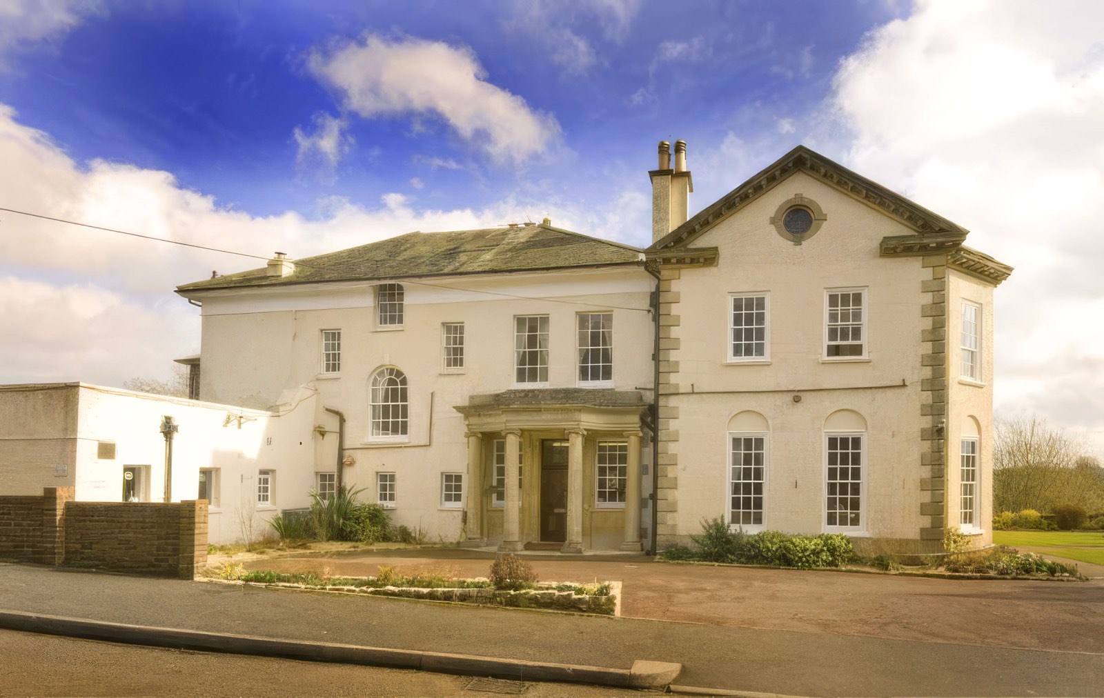 Woodside View, an Edwardian mansion with a columned entrance, set behind lawns